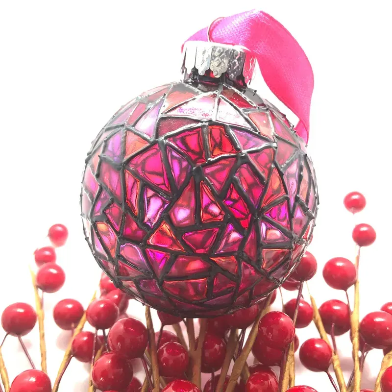 A bright pink hand-painted Christmas ball ornament with a stained-glass effect