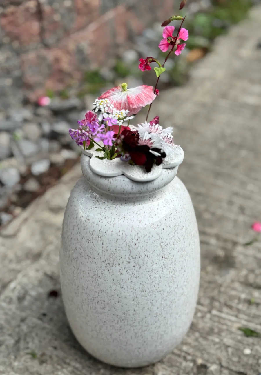 A white clay flower arranger holding a small floral display on a vase