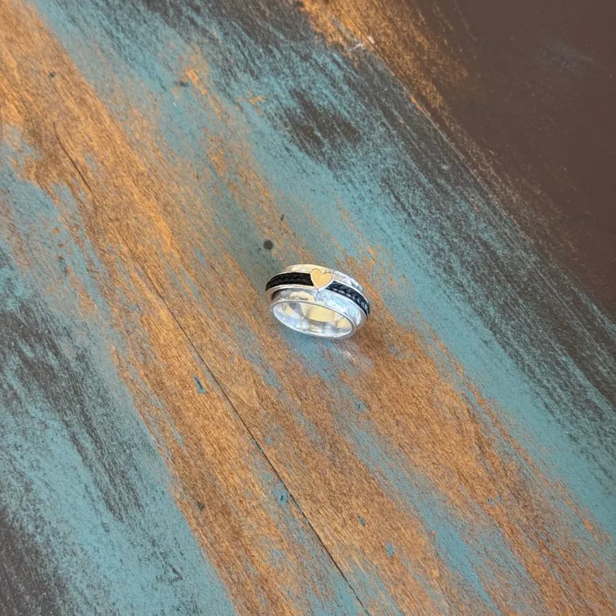 A horsehair ring with a small gold heart detail on a painted wooden surface