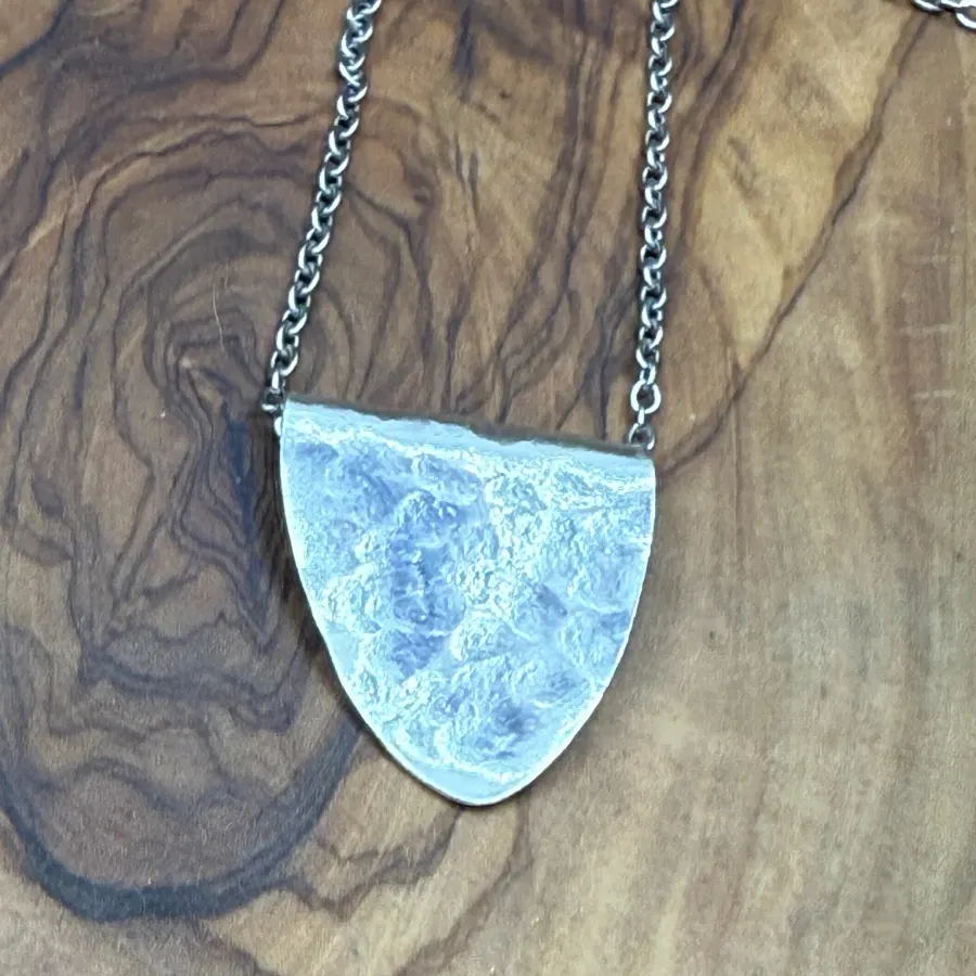A small hammered silver spoon bowl pendant on a chain