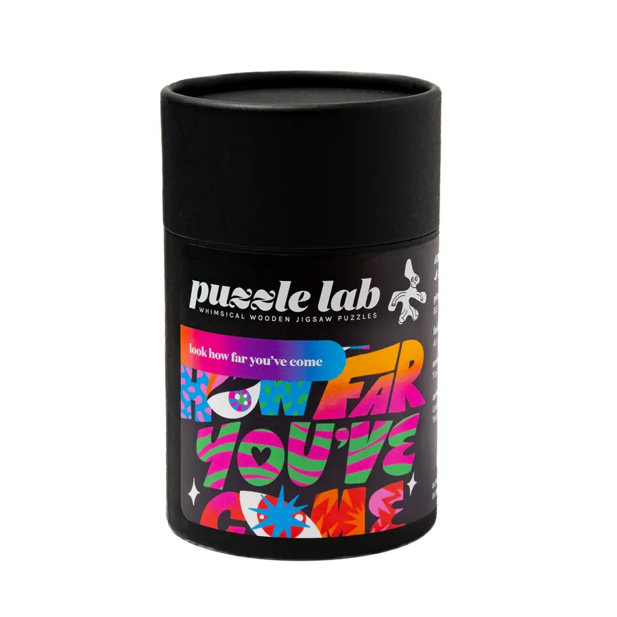 Puzzle Lab’s black cylindrical packaging for Look How Far You’ve Come, with colourful artwork by Tim Singleton