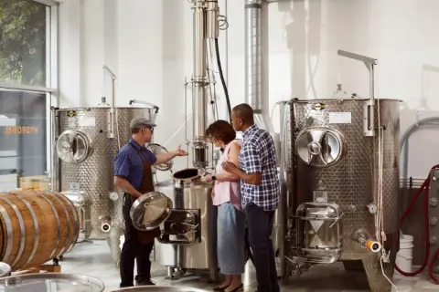 A guide showing visitors the still and fermentation tanks at Apikol