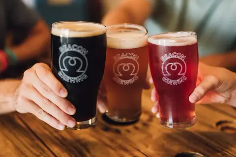 Three Beacon Brewing pint glasses of dark, amber and red beer