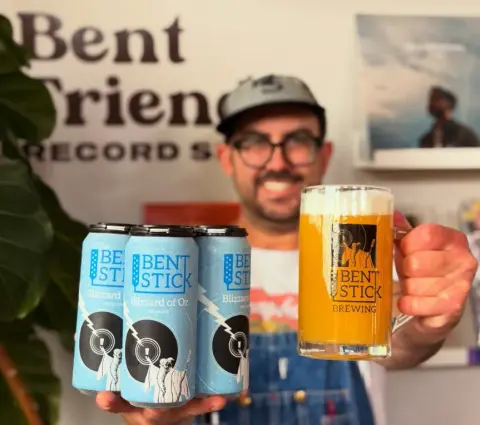 Cans of Bent Stick Blizzard of Oz white IPA with a pint mug