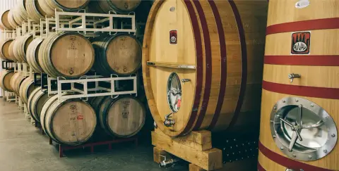 Oak barrels and foudres marked with the Auval logo in the brewery