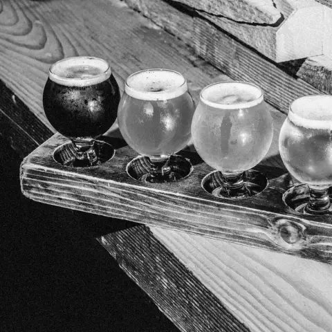 A flight of four Brassneck beers on a wooden paddle