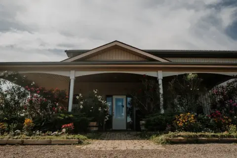 The Cornerstone Estate Winery tasting room entrance with a covered porch and flower beds