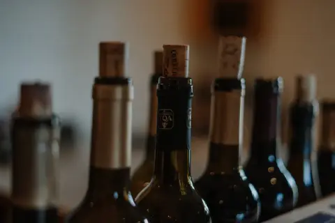 Several wine bottles with corks, arranged in a row, with a focus on the central bottle.