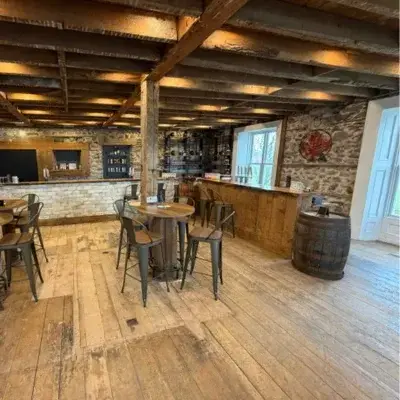 The Crimson Cider tasting room in the old stone house, with wood beams, a bar and barrel