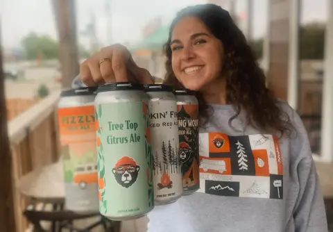 Dark Woods Tree Top Citrus Ale cans held up at the Innisfail taproom