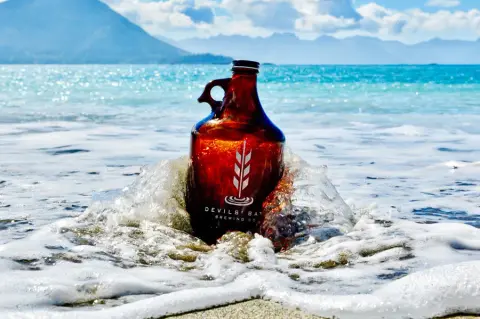 Devils' Bath Brewing growler in the surf near Port McNeill