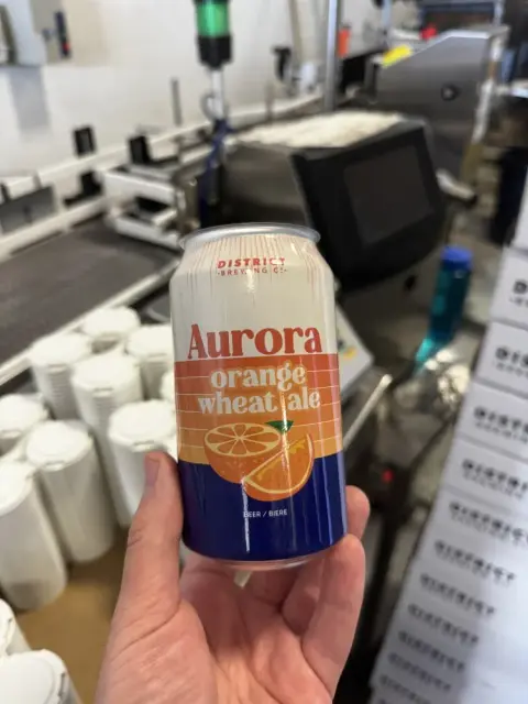District Aurora Orange Wheat Ale can at the canning line