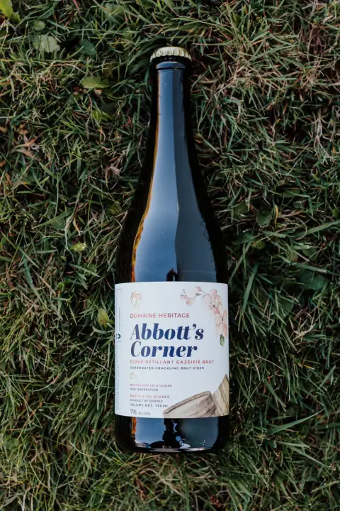 A bottle of Domaine Héritage Abbot's Corner cider in the grass