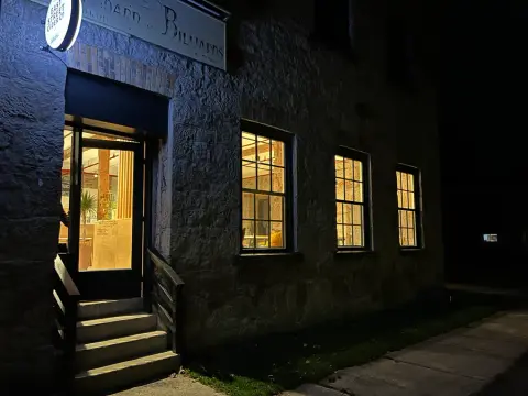 The lit entrance of the East Street Cider taproom in the old stone foundry building at night