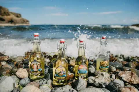 Swing-top bottles of Fossil Beach Farm cider on the beach at Hornby Island