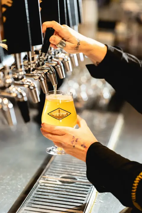 A Glasstown beer poured from the tap into a logo glass