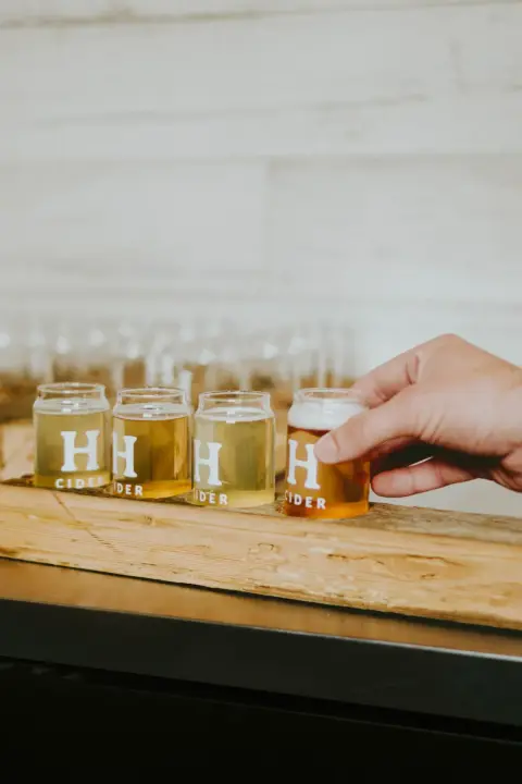 A tasting flight of four Homestead ciders on a wooden board