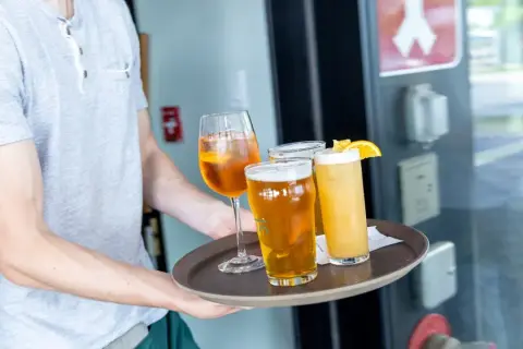 Server carrying a tray of beers at La Chope Angus