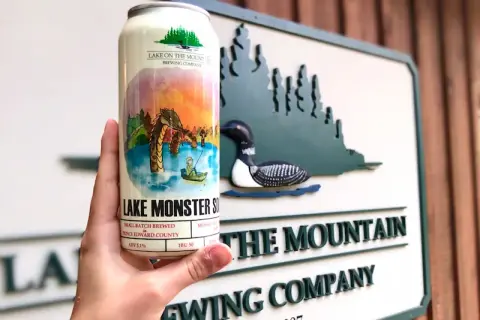 Can of Lake Monster sour in front of the Lake on the Mountain Brewing Company sign