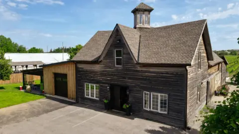 The Leaning Post winery barn with a cupola, beside the vineyard in Stoney Creek