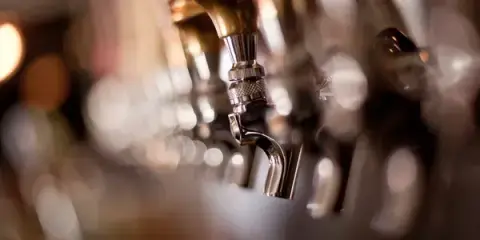 Close-up of beer taps in a bar with soft lighting and bokeh effect.