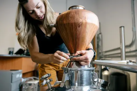 Woman working with a piece of equipment that has a large, wooden, cone-shaped component, possibly related to scientific or industrial proces