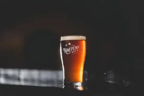 A pint of amber ale in a Ninepenny Brewing glass