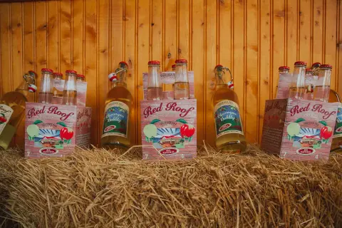 Bottles and boxes of Red Roof and Okanagan Bubbly cider stacked on straw bales