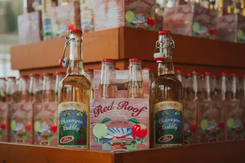 Okanagan Bubbly bottles and a Red Roof box on the shelves of the cidery shop