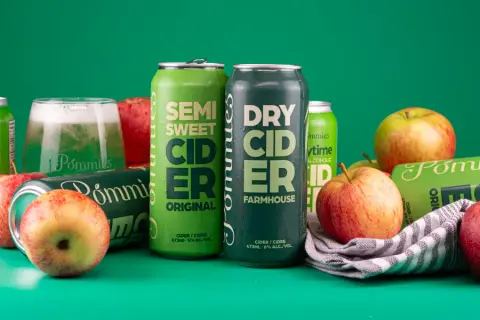 Cans of Pommies Original semi-sweet cider and Pommies Farmhouse dry cider with fresh apples