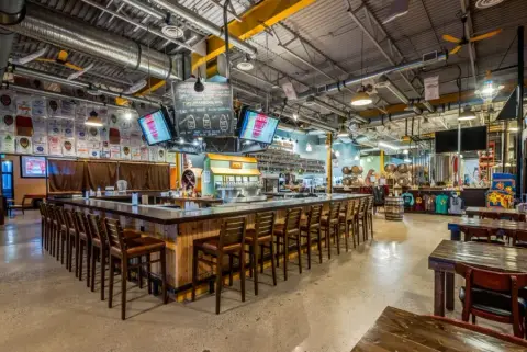 A wide-angle view of Prairie Dog Brewing's Calgary Chinook Brewpub dining room, with large square central bar surrounded by seats and tables