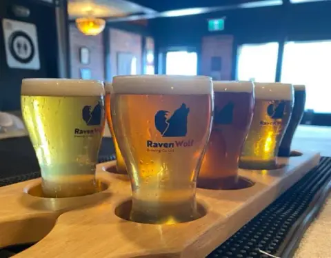 A flight of RavenWolf beers in logo glasses on the taproom bar