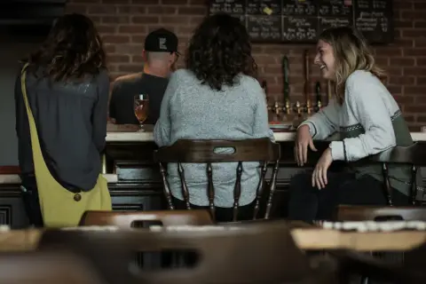 Friends at the bar of the Red Hart taproom, with the tap wall and chalkboard beer list behind
