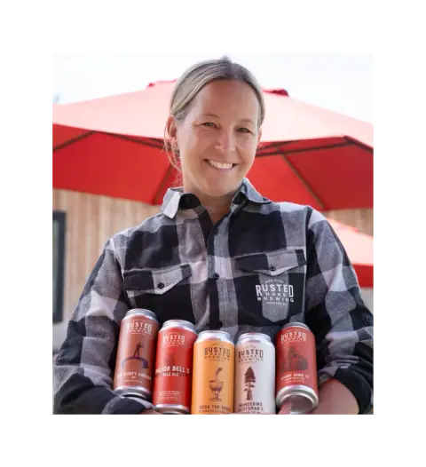 A Rusted Rake team member holding a row of the brewery's cans