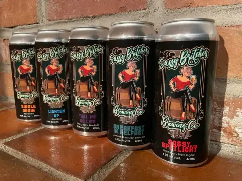 A can and mug of Sassy Britches beer on a wooden table