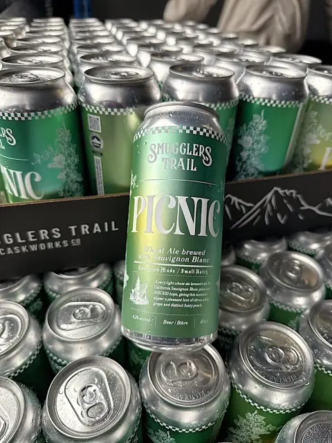 Cans of Smugglers Trail Picnic wheat ale stacked at the brewery