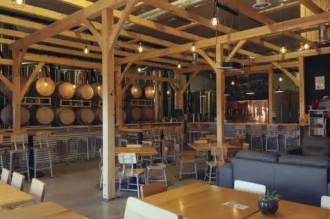 The timber-frame Snake Lake taproom with barrels and brewing tanks behind the bar