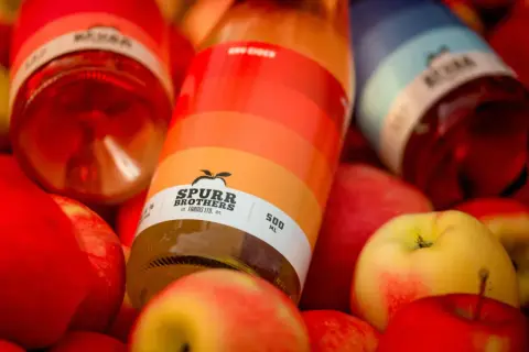 Spurr Brothers cider bottles on a bed of apples