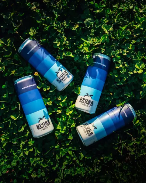 Cans of Spurr Brothers Wild Blueberry cider on clover