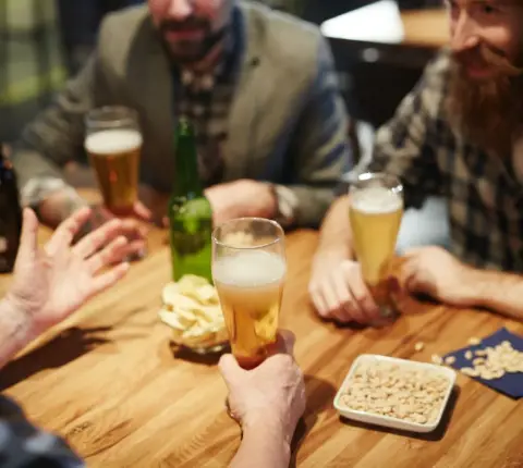 Some friends sitting at Stonyslope Brewing Company, at a wooden table enjoying some beers