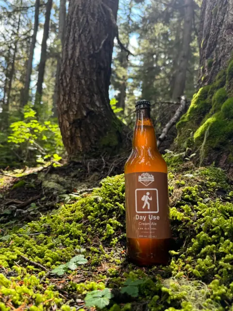 A bottle of Switchback Day Use Cream Ale on moss in the forest