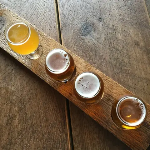 A flight of four Beer Farmers beers on a wooden paddle
