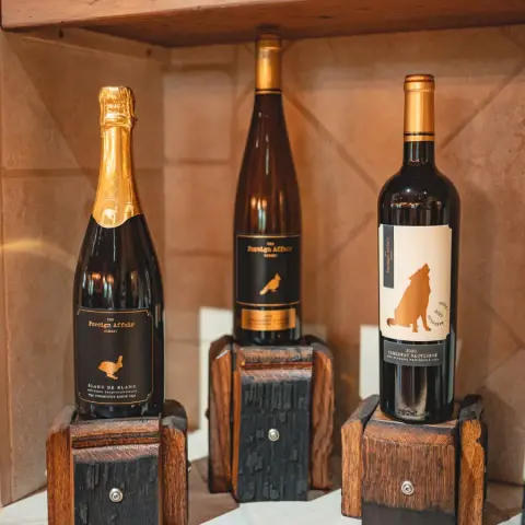 Foreign Affair Blanc de Noirs, Riesling and red wine bottles displayed on wooden stands