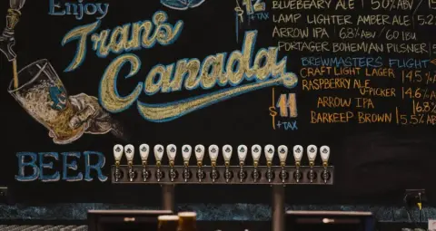 The chalkboard beer menu and tap wall at the Trans Canada Brewing taproom