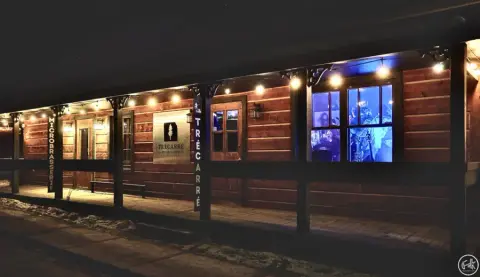The log-sided front porch of Trécarré Microbrasserie in Saint-Côme, lit up on a winter evening