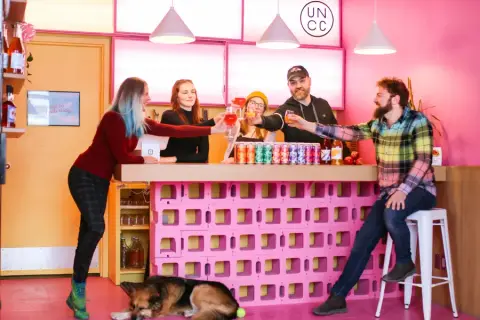The pink tap room bar at Uncommon Cider in Calgary, stacked with cans of cider