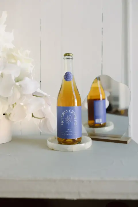 Bottles of Victoria Cider Co. cider with blue labels on a white shelf