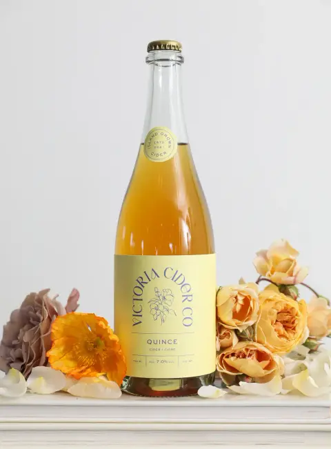 Bottle of Victoria Cider Co. Quince cider among orange flowers