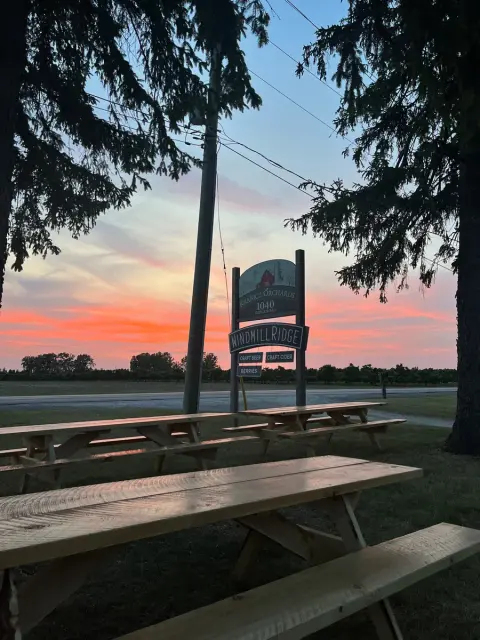 The Windmill Ridge sign and picnic tables at sunset