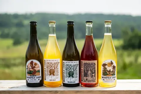 Five bottles of Woodfolk Cider with a scenic background